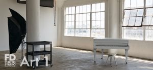 natural light photo studio with white staircase, white grand piano, concrete and wood walls