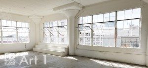 natural light photo studio with white staircase, white grand piano, concrete and wood walls