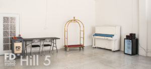 Photo Studio with white concrete floors, shabby chic piano and a bellman cart for rental in LA