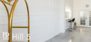 Romantic photo studio with white frames wall, gold bellman cart and white concrete for rental in Los Angeles
