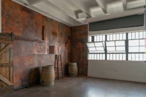 South-East Facing Natural light photo studio with wood barn doors, wood barrels, red phone booth and a rust corner available for photo and video rental in Los Angeles