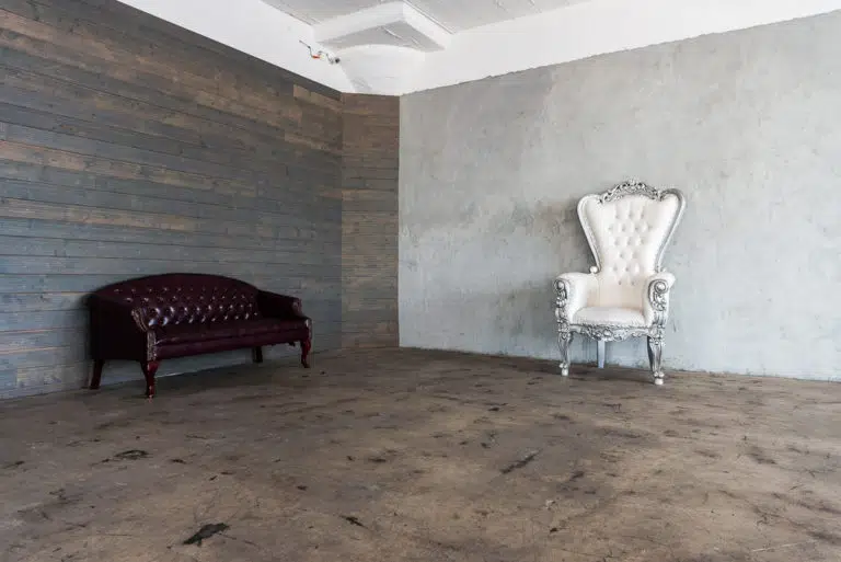 Photo and Video studio with concrete textured wall, red sofa and white extra large chair available for rental In Los Angeles
