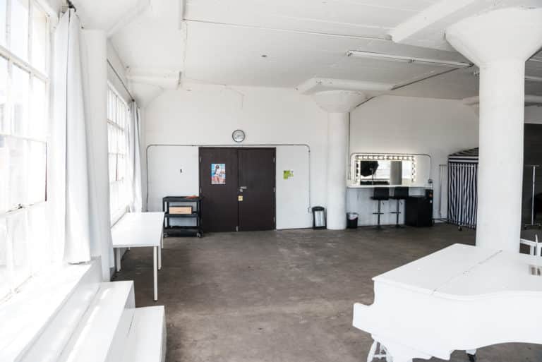 Photo and Video studio with concrete textured wall, red sofa and white extra large chair available for rental In Los Angeles
