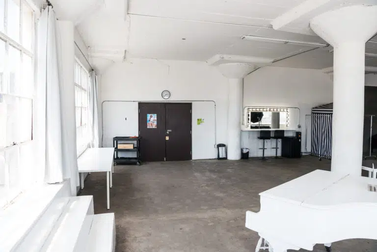 Photo and Video studio with concrete textured wall, red sofa and white extra large chair available for rental In Los Angeles