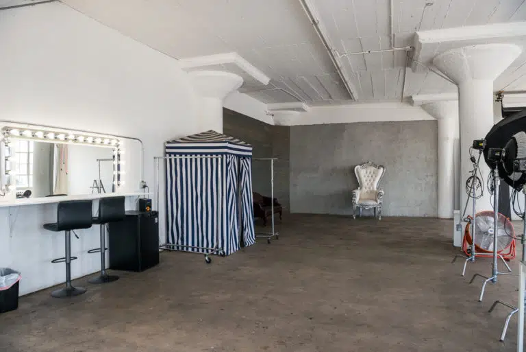 Photo and Video studio with concrete textured wall, red sofa and white extra large chair available for rental In Los Angeles