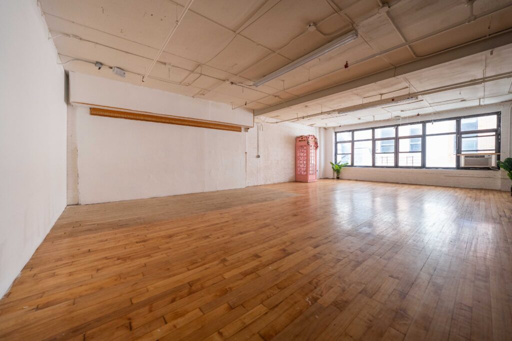 Astoria 3 - photo studio with large window, brick walls, wooden floor and a photo booth FD Photo STudio NY