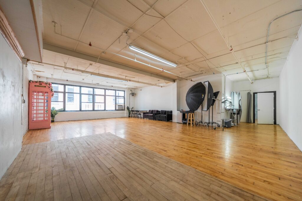 Astoria 3 - photo studio with large window, brick walls, wooden floor and a photo booth FD Photo STudio NY