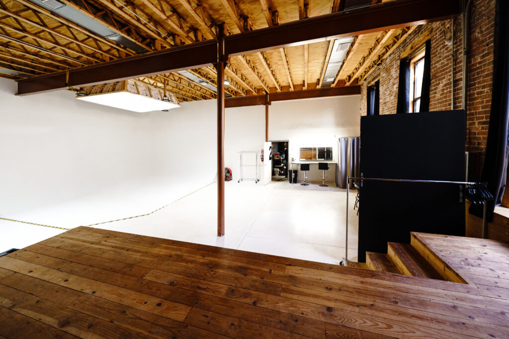 Large daylight photo studio with cyc-wall, tall windows, grand piano, and wooden platform near you Chicago 2