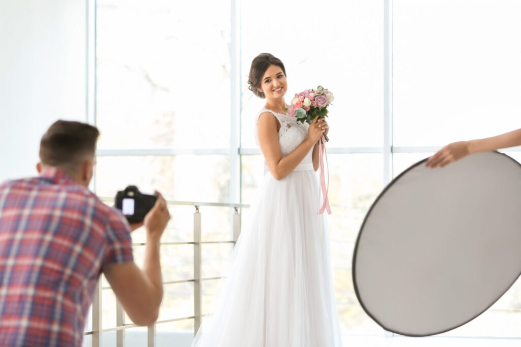 Professional photographer taking photo of beautiful bride in studio
